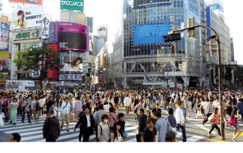 Shibuya Crossing yang ramai di malam hari, dikelilingi toko-toko trendi dan lampu neon, destinasi utama **wisata belanja di Jepang** di **Shibuya**, Tokyo.